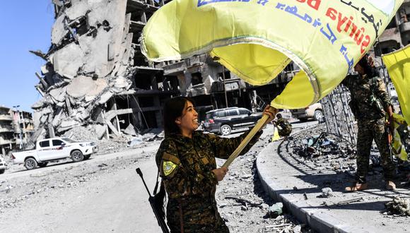 Rojda Felat ondea la bandera de las milicias kurdas  en la emblemática rotonda al-Naim de Raqqa, donde los terroristas decapitaban a civiles. (AFP).