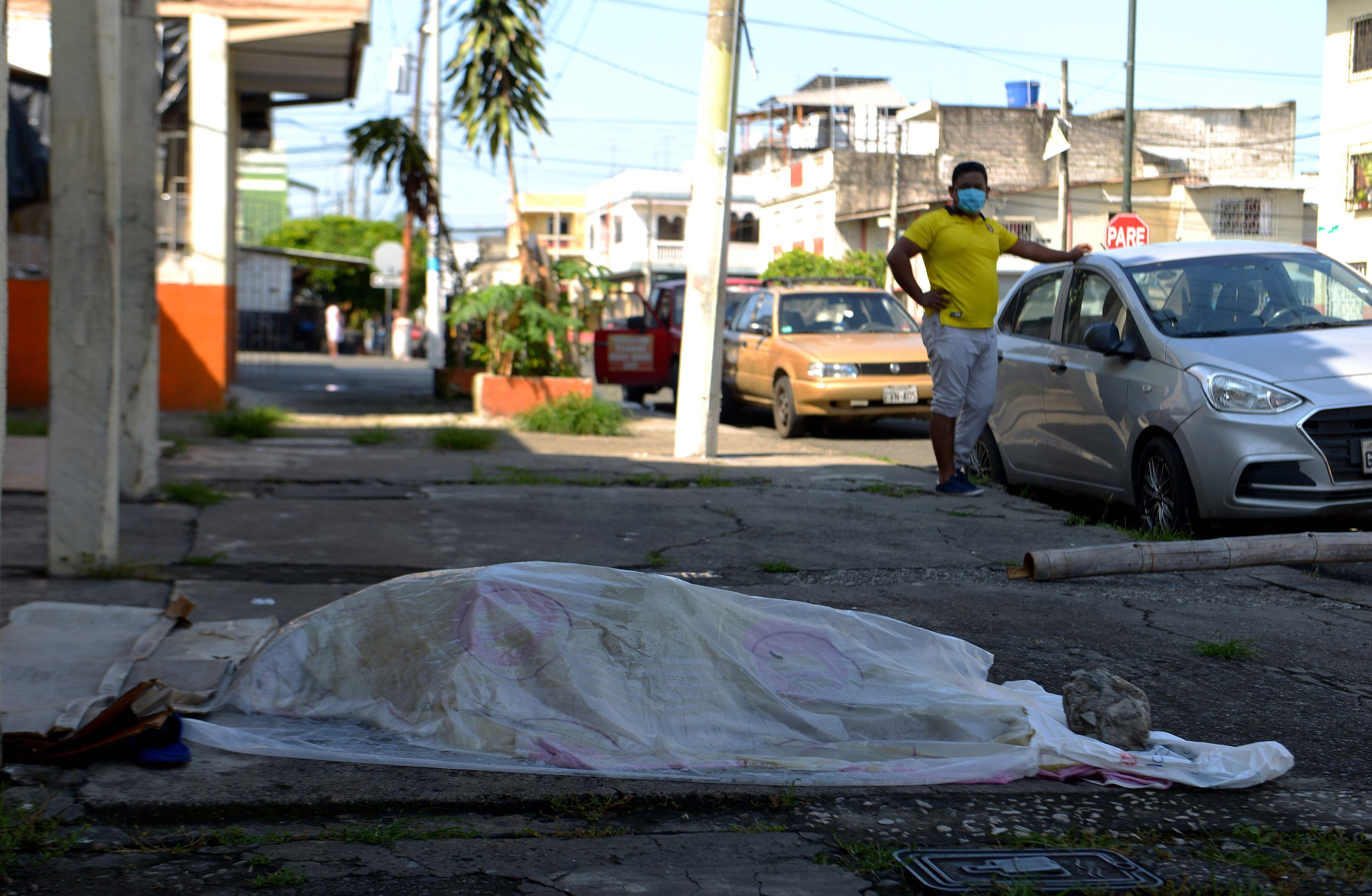 Un hombre mira el cuerpo de una persona que estuvo tres días fuera de una clínica en Guayaquil, el epicentro del coronavirus en Ecuador. (AFP / Pin de Marcos / Str).