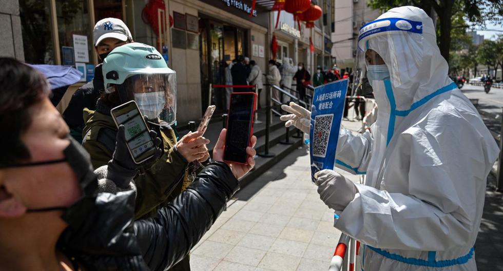Un trabajador muestra un código QR a los clientes para verificar su estado de salud antes de que ingresen a un mercado en el distrito de Jing'an, en Shanghai, China, el 29 de marzo de 2022. (Héctor RETAMAL / AFP).