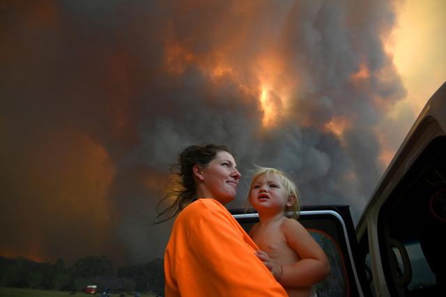 Sharnie Moren y su hija Charlotte, de 18 meses, observan cómo el humo espeso sale de los incendios forestales cerca de Nana Glen, cerca de Coffs Harbour, Australia. (Reuters)