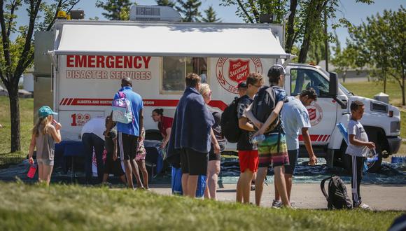 Un vehículo EMS del Ejército de Salvación está configurado como una estación de enfriamiento mientras las personas se alinean para ingresar a un parque acuático mientras intentan combatir el calor en Calgary, Alberta, Canadá. (Foto: Jeff McIntosh / The Canadian Press vía AP).