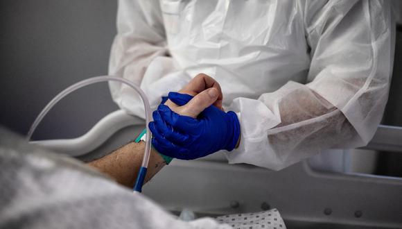 Una enfermera toma la mano de un paciente infectado con coronavirus en la unidad de cuidados intensivos del hospital Lyon-Sud en Pierre-Benite, Francia. (Foto de JEFF PACHOUD / AFP).