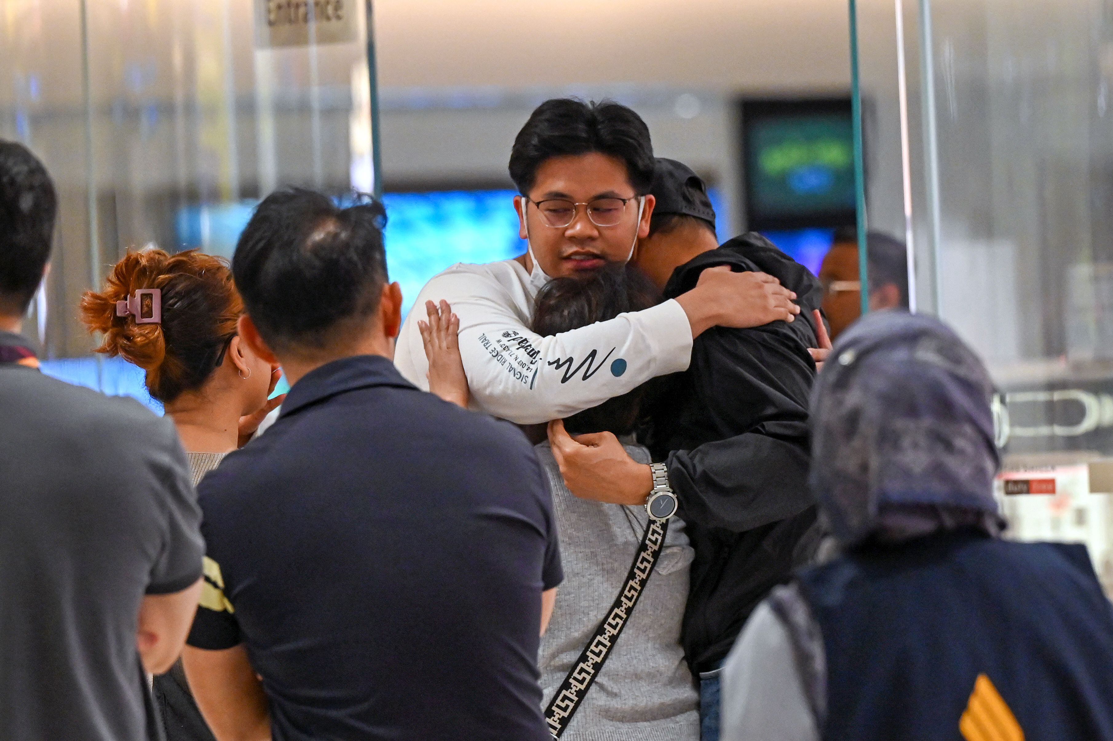 Los pasajeros del vuelo SQ321 de Singapore Airlines de Londres a Singapur, que realizó un aterrizaje de emergencia en Bangkok, saludan a sus familiares a su llegada al aeropuerto Changi de Singapur el 22 de mayo de 2024. (Foto de Roslan RAHMAN / AFP)