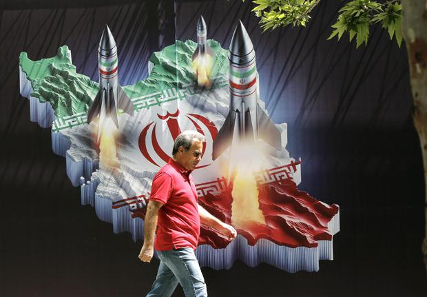 Un iraní pasa junto a una enorme pancarta antiisraelí con imágenes de misiles en el mapa de Irán, en Teherán, el 19 de abril de 2024. (EFE/EPA/ABEDIN TAHERKENAREH).