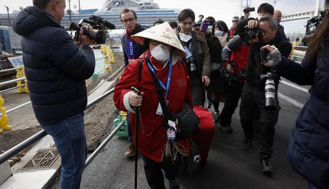 Una pasajera es rodeada por varios medios de comunicación después de que desembarcó del crucero Diamond Princess. (AP).
