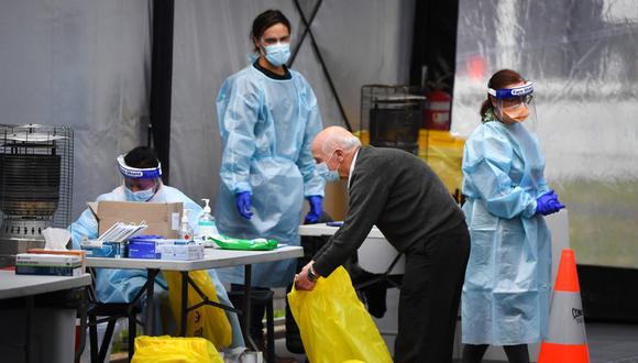 Un mensajero recolecta hisopos tomados en una clínica de pruebas en Melbourne. El estado de Victoria, afectado por el COVID-19, informó una caída importante en los casos de nuevos. (William WEST / AFP)