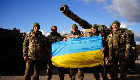 Soldados ucranianos que entrenan en el Bovington Camp británica posan con una bandera ucraniana frente a un tanque FV 4034 Challenger 2, en el suroeste de Inglaterra, el 22 de febrero. 2023. (Foto de Ben Birchall / POOL / AFP)