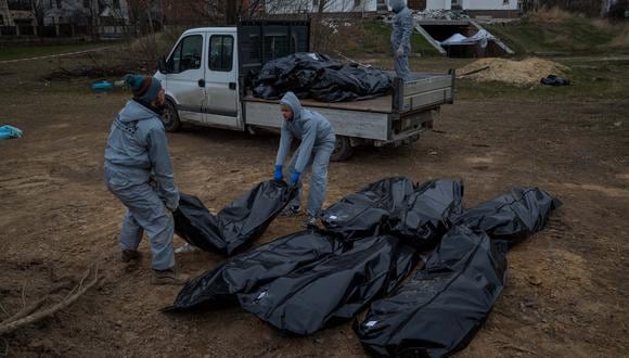 Autoridades forenses recogen cadáveres envueltos en plásticos para su traslado a la morgue en Bucha (Ucrania). (EFE/ Miguel Gutiérrez)