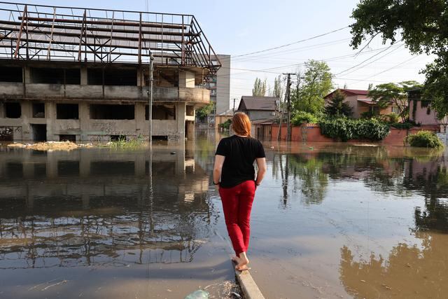 Una mujer mira una calle inundada en la ciudad de Kherson, luego de las inundaciones causadas por los daños sufridos en la represa Kakhovka HPP, el 6 de junio de 2023. (Foto de STRINGER / AFP)