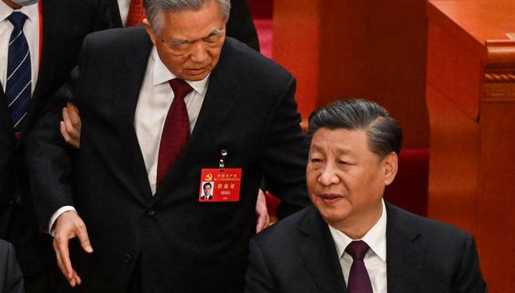 El presidente de China, Xi Jinping (der.), habla con el expresidente Hu Jintao mientras lo ayudan a salir de la ceremonia de clausura del 20 Congreso del Partido Comunista de China, el 22 de octubre de 2022. (Noel CELIS / AFP).