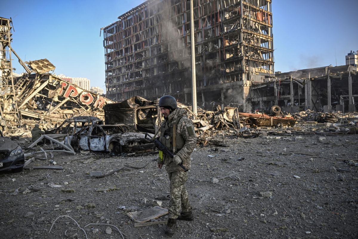 A Ukrainian military man walks through the rubble of the Retroville shopping center in kyiv, destroyed by a Russian attack.  (ARIS MESINIS / AFP).