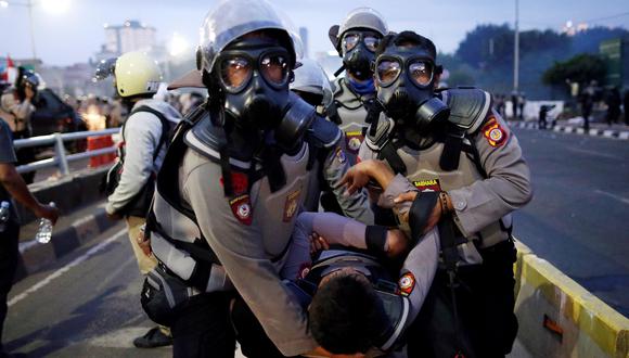 Los agentes de la policía antidisturbios de Indonesia llevan a un colega herido durante un enfrentamiento con estudiantes fuera del edificio del Parlamento en Yakarta. (EFE / EPA / MAST IRHAM).