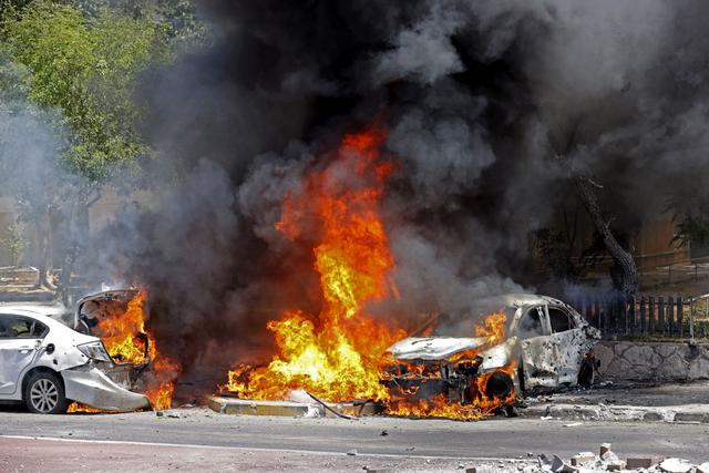 Carros en llamas después de que un cohete lanzado desde la Franja de Gaza impactara contra ellos en la ciudad de Ashkelon. (Foto de JACK GUEZ / AFP).