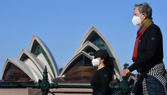 Dos personas pasan por la Ópera de Sídney, Australia, durante el confinamiento para frenar los contagios de coronavirus. (EFE / EPA / MICK TSIKAS AUSTRALIA Y NUEVA ZELANDA).