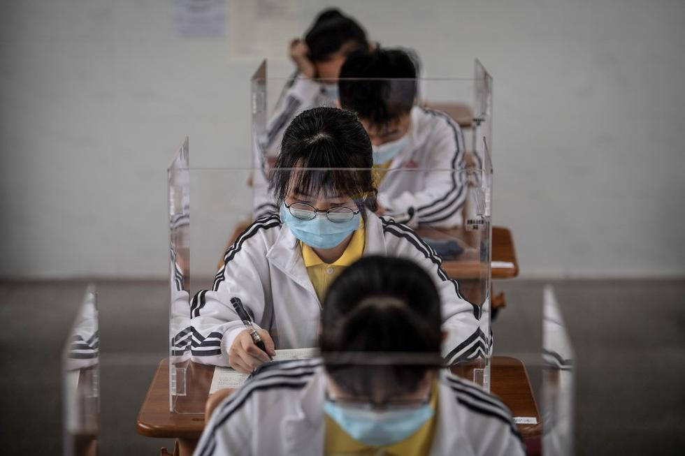 Los estudiantes de último año de secundaria estudian mascaras y plásticos protectores en un aula en Wuhan. (STR / AFP)