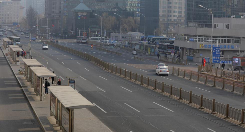 Funcionarios de salud chinos con trajes protectores que verificaron el cuerpo de un hombre con una máscara facial que se derrumbó y murió en una calle cerca de un hospital en Wuhan. (Imagen referencial / AFP)