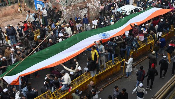Un grupo de manifestantes se detiene con una gran bandera india frente a la mezquita Jama Masjid, en una manifestación contra la nueva ley de ciudadanía en Nueva Delhi. (AFP)