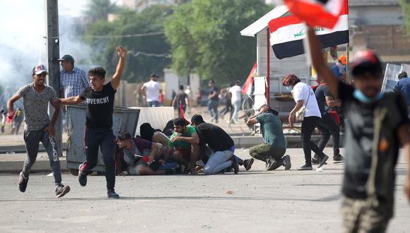 Los manifestantes iraquíes se refugian mientras las fuerzas de seguridad dispersan a las multitudes en el centro de Bagdad durante las manifestaciones antigubernamentales. (AFP)