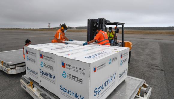 Trabajadores del aeropuerto transportan cajas con algunas de las 100.000 dosis de la vacuna rusa Sputnik V contra el coronavirus COVID-19 que llegaron a Venezuela el 29 de marzo de 2021. (Foto de Federico PARRA / AFP).