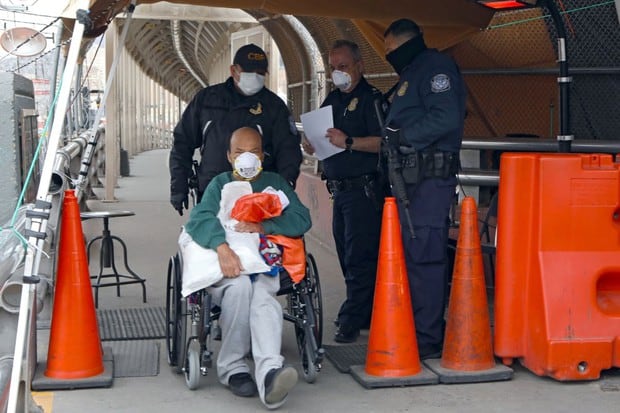 Agentes de la Oficina de Aduanas y Protección Fronteriza de los Estados Unidos empujan la silla de ruedas de un migrante mexicano mientras es deportado en el Puente Internacional Paso del Norte-Santa Fe en Ciudad Juárez, estado de Chihuahua (Foto: AFP)