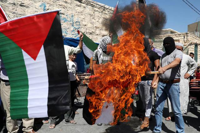 Manifestantes palestinos queman la bandera de los Emiratos Árabes Unidos (EAU) durante una protesta en la ciudad de Yata, cerca de Hebrón, Cisjordania. (EFE/EPA/ABED AL HASHLAMOUN).