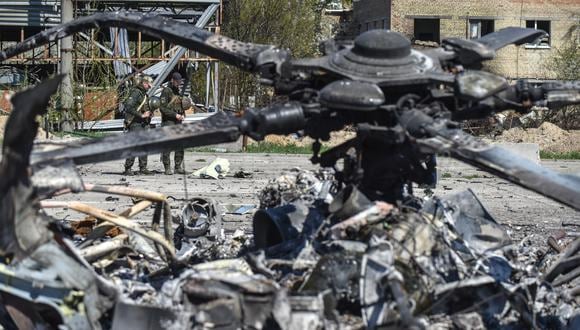 Fotografía tomada durante un viaje organizado por el Ministerio del Interior de Ucrania que muestra a militares ucranianos cerca de los restos de un helicóptero ruso en el aeródromo de Gostomel cerca de Kyiv (Kiev). (EFE/EPA/OLEG PETRASYUK)
