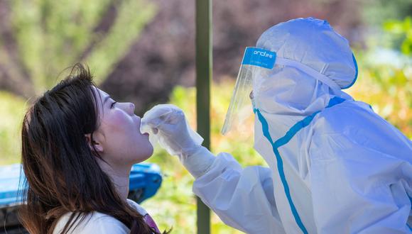Un trabajador de salud realiza una prueba de coronavirus a una mujer en la Universidad de Wuhan. (Foto: AFP )
