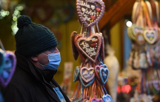 Un empleado usa una máscara protectora frente a un puesto de ventas en la entrada del mercado navideño en Landshut, sur de Alemania. (Foto: Christof STACHE / AFP)