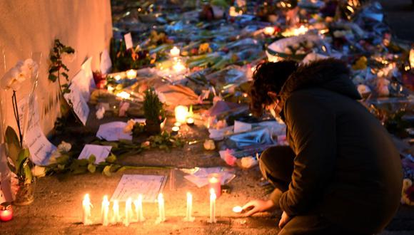 Un niño enciende una vela en la entrada de una escuela secundaria en Conflans-Sainte-Honorine, a 30 kilómetros al noroeste de París, el 17 de octubre de 2020, después de que un maestro fuera decapitado por un atacante que fue abatido a tiros por la policía de Francia. (Foto de Bertrand GUAY / AFP).