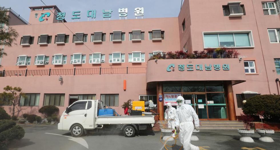 Funcionarios de salud de Corea del Sur rocían desinfectante frente a un hospital donde ahora se han identificado un total de 16 infecciones de COVID-19. (AFP)