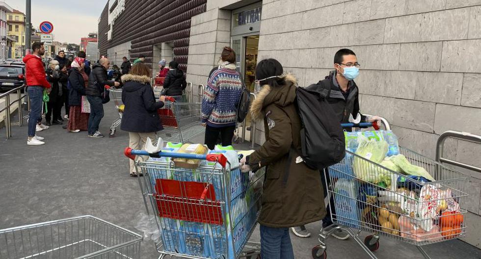 Italia es el país con mayor índice de letalidad del mundo por el coronavirus. En la imagen, personas que usan máscaras protectoras salen de un supermercado de Milán con carros llenos de compras. (Foto: AFP)