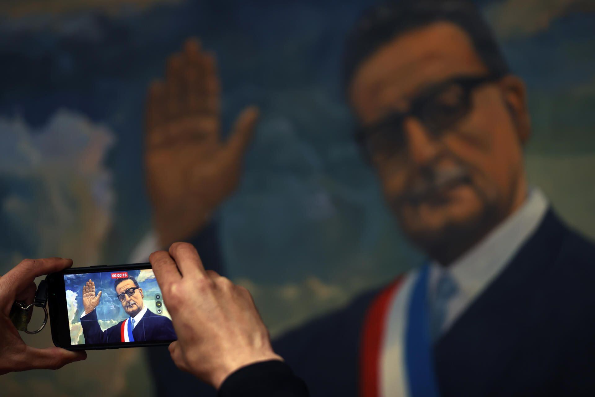 A man takes a recording of a painting by Salvador Allende, on August 30, 2023. (EFE/ Elvis González).