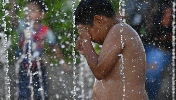 Un niño se refresca del calor abrasador en las aguas de una fuente en la plaza cívica del centro histórico de San Salvador, el 27 de febrero de 2024. (Foto de Marvin RECINOS / AFP)