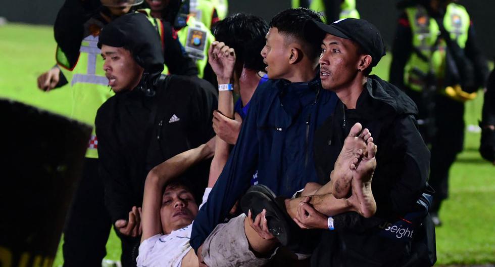 Un grupo de personas carga a un hombre en el estadio Kanjuruhan en Malang, en Indonesia. (AFP).