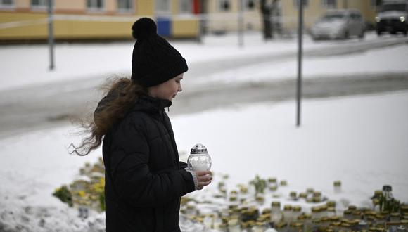 Una niña pone una vela en un monumento improvisado frente a la escuela Viertola en Vantaa, en el norte de la capital finlandesa, Helsinki, un día después de que un niño de 12 años abriera fuego dentro de la escuela, matando a un compañero de clase e hirió gravemente a otros dos niños. (Foto de Olivier MORIN / AFP)