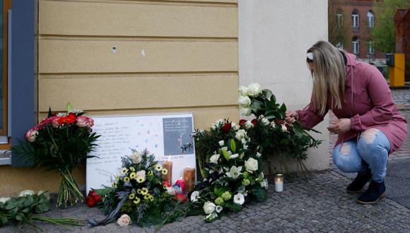 Esta foto de archivo tomada el 29 de abril de 2021 muestra a una mujer colocando flores para las víctimas frente al centro de atención de Oberlin en Potsdam, en el este de Alemania. (ODD ANDERSEN / AFP).