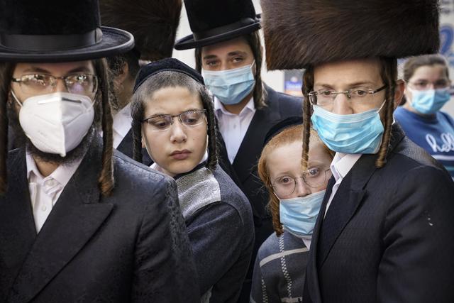 Miembros de la comunidad judía ortodoxa se reúnen alrededor de un periodista en medio de la pandemia del coronavirus en el vecindario de Borough Park del distrito de Brooklyn de Nueva York (Estados Unidos). (AP / John Minchillo).