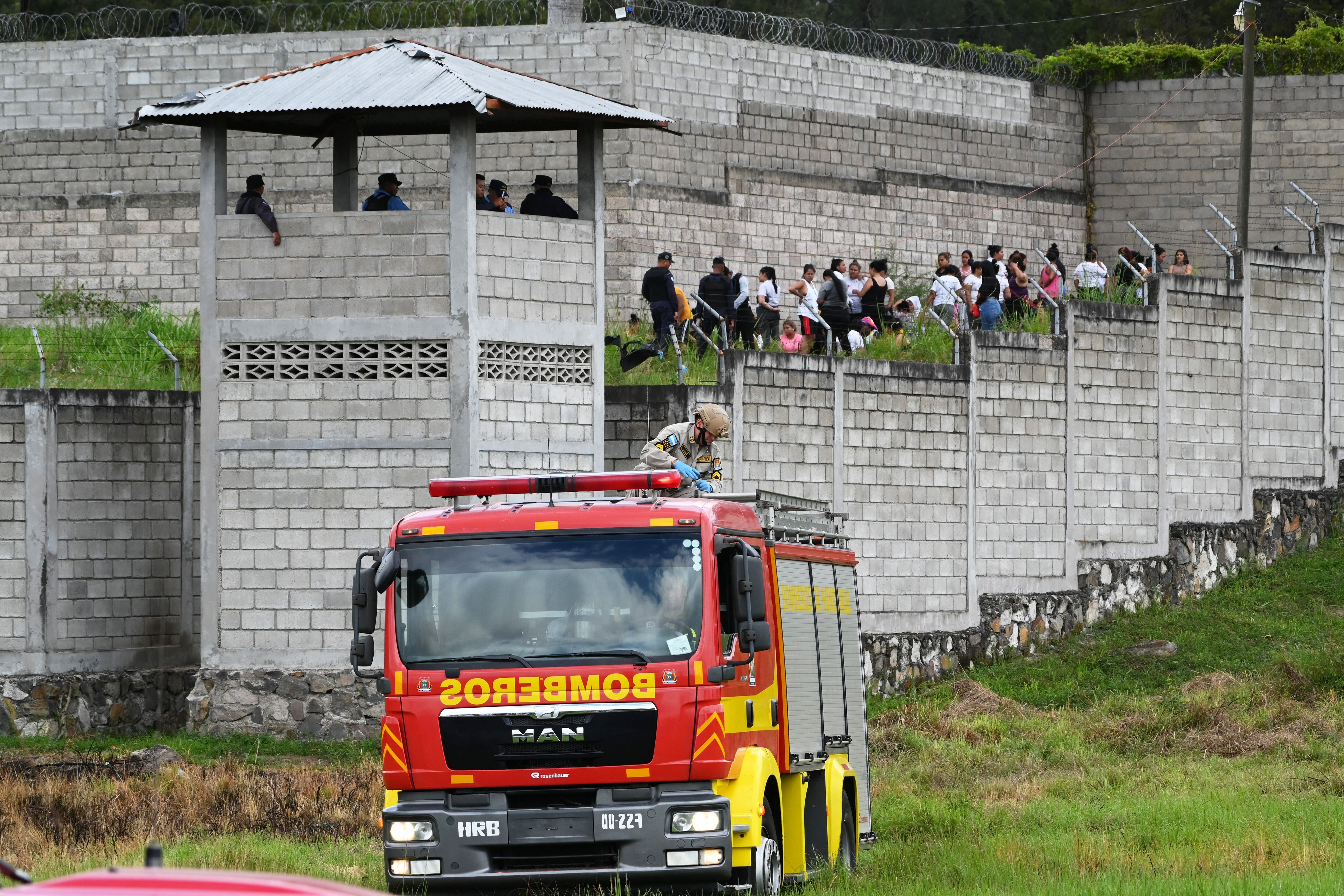 Prison guards guard inmates at the Centro de Adaptación Social de la Mujer (CEFAS) prison after a fire following a fight between inmates in Tamara, some 25 km from Tegucigalpa, Honduras, on June 20, 2023. (Photo by Orlando SIERRA / AFP)