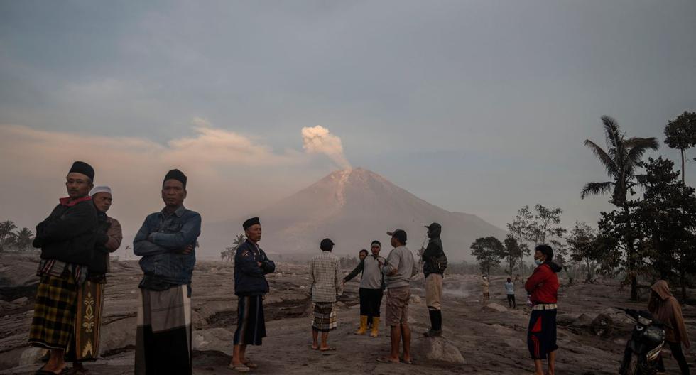 La gente se para frente al volcán Semeru luego de una erupción en el pueblo de Kajar Kuning, en Lumajang, Indonesia, el 5 de diciembre de 2022. (JUNI KRISWANTO / AFP).