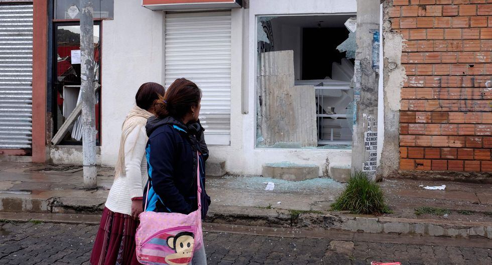 Dos mujeres caminan frente a una tienda vandalizada durante las protestas de los partidarios del ex presidente boliviano Evo Morales después de su renuncia. (AFP / JORGE BERNAL). Dos mujeres caminan frente a una tienda vandalizada durante las protestas de los partidarios del ex presidente boliviano Evo Morales después de su renuncia. (AFP / JORGE BERNAL).