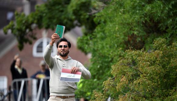 El manifestante Salwan Momika sostiene el libro sagrado musulmán y una hoja de papel que muestra la bandera de Irak durante una protesta frente a la embajada iraquí en Estocolmo, Suecia. (Foto de Oscar Olsson / Agencia de noticias TT / AFP)