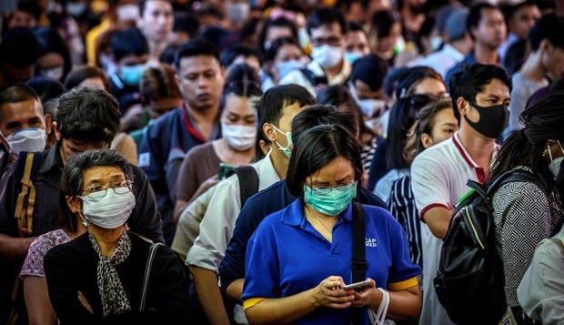 Viajeros, que usan máscaras en medio del temor a la propagación del nuevo coronavirus, esperan una embarcación en Bangkok. Imagen del 2 de marzo de 2020. (AFP).