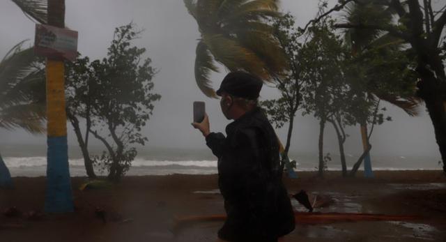 Una mujer graba las fuertes olas y la velocidad del viento debido al paso de la tormenta Laura en Arroyo, sur de Puerto Rico. (Foto: EFE/ Thais Llorca).