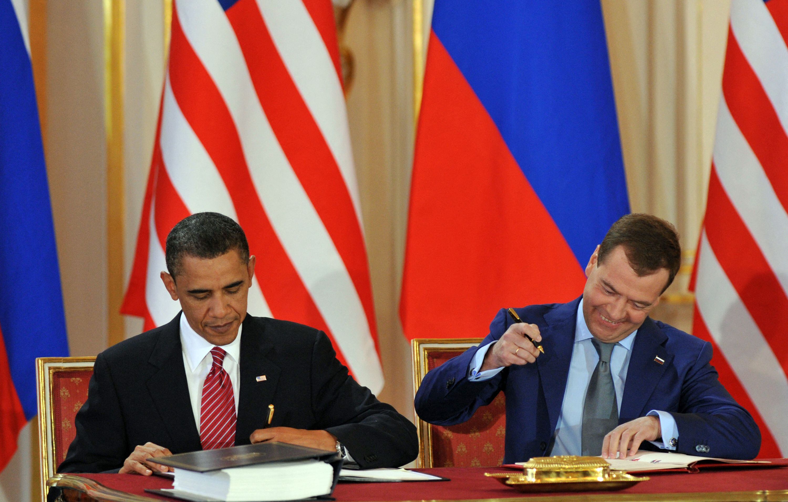 US President Barack Obama (left) and Russian President Dimitri Medvedev sign the New START in Prague on April 8, 2010. (Photo by Yuri KADOBNOV / AFP)