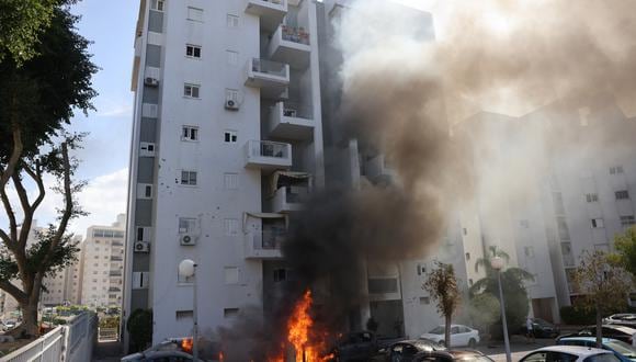 Los coches estacionados frente a un edificio residencial se incendian durante un ataque con cohetes desde la Franja de Gaza contra la ciudad de Ashkelon, en el sur de Israel, el 7 de octubre de 2023. (Foto de AHMAD GHARABLI / AFP)
