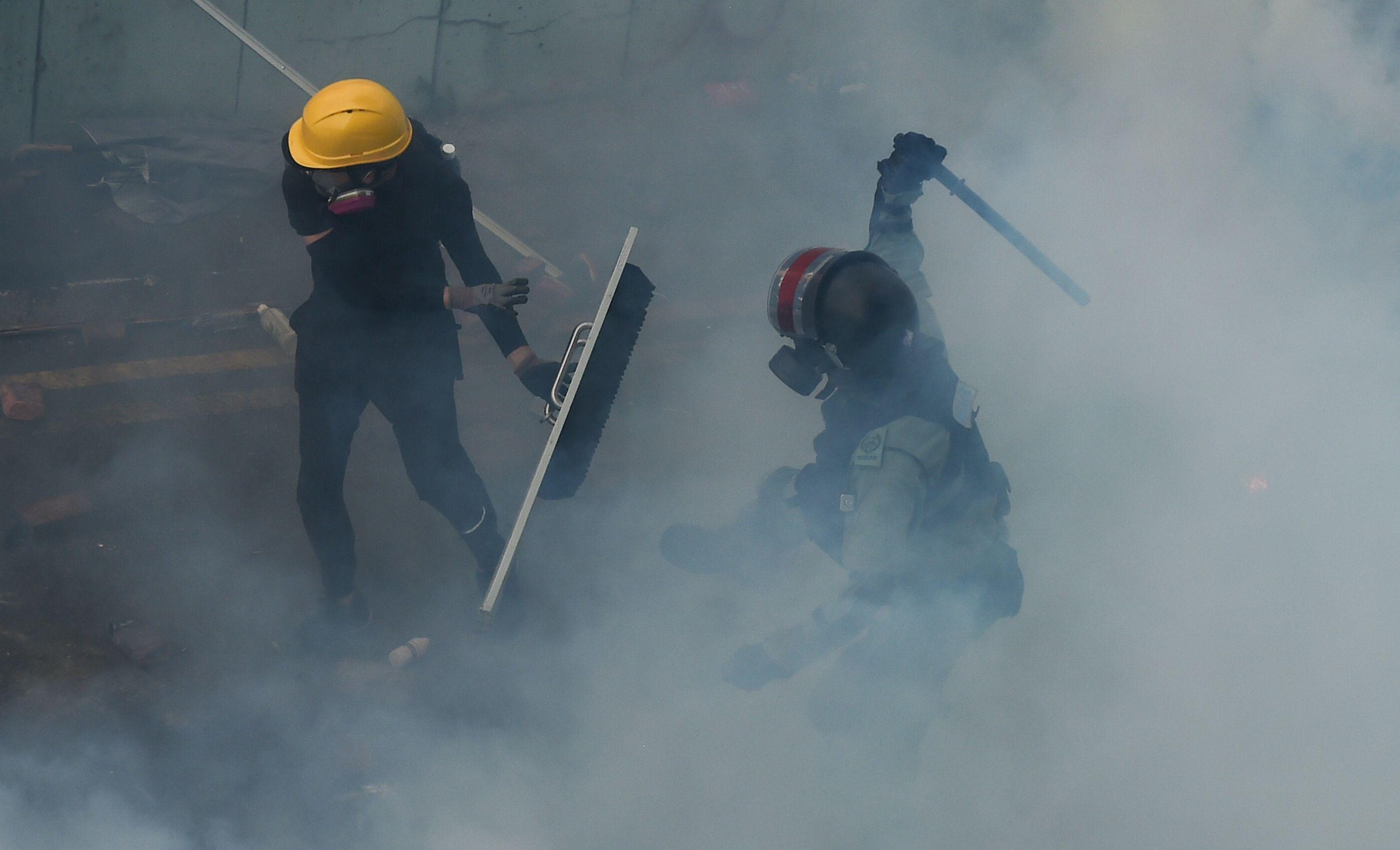 Un manifestante es golpeado por la policía antidisturbios mientras intentaba encontrar una salida segura del campus de la Universidad Politécnica de Hong Kong. (Foto por Ye Aung Thu / AFP).