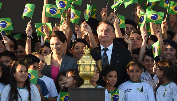 El presidente brasileño Jair Bolsonaro (derecha) y la primera dama Michelle Bolsonaro están rodeados de niños junto a una urna con el corazón de Don Pedro I, en Brasilia, el 23 de agosto de 2022. (Foto por EVARISTO SA / AFP)