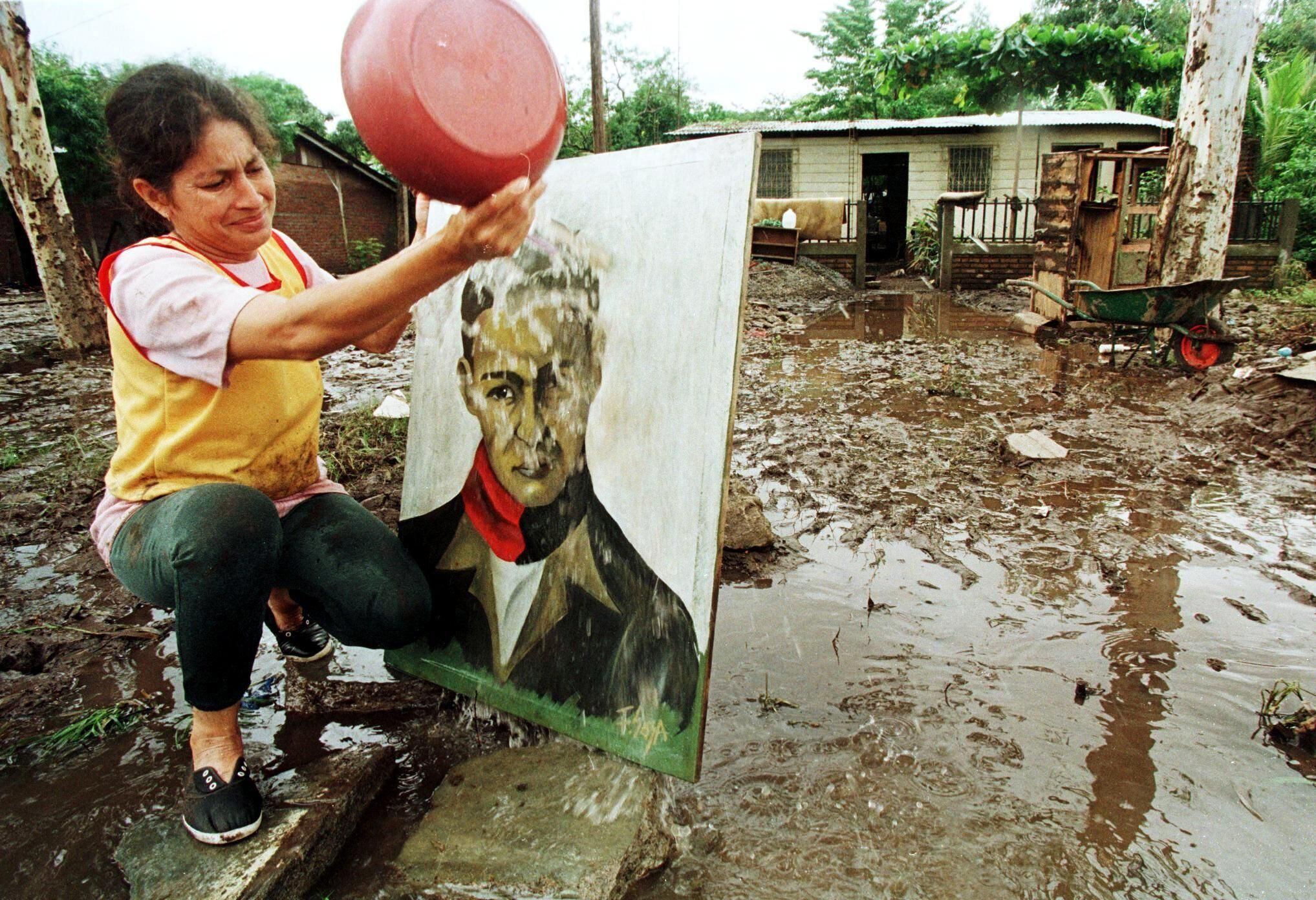 A Nicaraguan woman cleans mud from Sandino's portrait after suffering the devastation of Hurricane Mitch in 1998. (GETTY IMAGES).