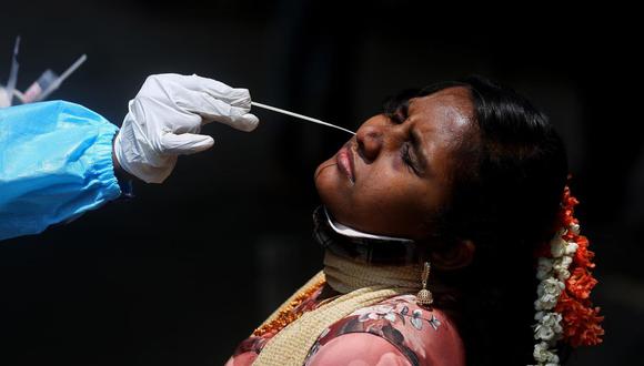 Un trabajador de la salud toma una muestra de hisopo nasal de una mujer para la prueba de coronavirus COVID-19 en la estación de tren de la ciudad de Bangalore, India, el 23 de abril de 2021. (EFE / EPA / JAGADEESH NV).