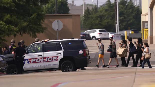 La gente levanta la mano al salir de un centro comercial tras los informes de un tiroteo, el sábado 6 de mayo de 2023, en Allen, Texas. (Foto AP/LM Otero).